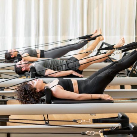 Class of diverse people doing the hundred pilates exercise on reformer beds in a gym in a healthy active lifestyle concept